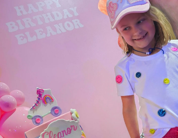 A colorful birthday celebration featuring a cake with roller skates, vibrant decorations, and bright, playful themes in a pink setting.