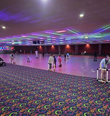 A spacious room filled with people skating on a smooth floor, enjoying the activity and socializing with one another.