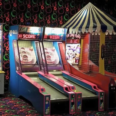 An arcade area featuring a "Slam-A-Winner" game and two ice-themed skee ball lanes, set against a colorful patterned wall.