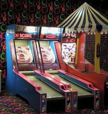 A row of colorful arcade games lined up in a well-lit game room, inviting players to enjoy classic gaming experiences.