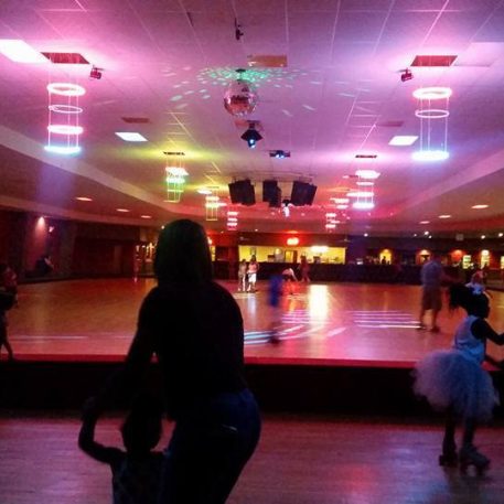 Colorful roller rink scene with skaters of all ages, vibrant lights, and a disco ball, creating a lively atmosphere.