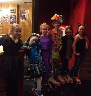 A group of girls in colorful costumes smiling and posing together for a photo.