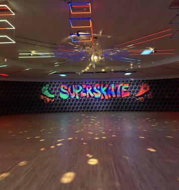 A vibrant dance floor illuminated by colorful lights, featuring a sign that reads "Supernova."