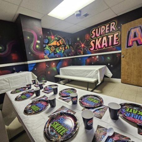 Colorful party room for "Super Skate," with decorated tables, vibrant wall art, and festive plates and cups.